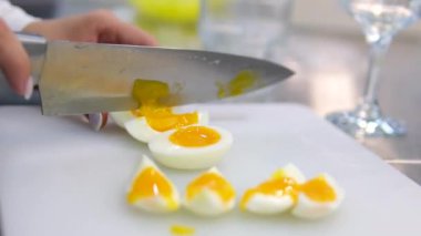 Haşlanmış yumurta kesmek. Dilimlenmiş yumurta dilimleri cam bir yüzeye düşer. Kadın elleri yakın mesafeden haşlanmış yumurtayı kesiyor.. 