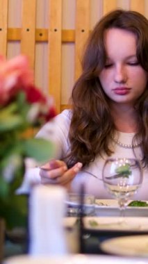 Kız telefona bakarken gülümsüyor. Genç bir kadın restoranda yemek yiyor, portakal suyu içiyor ve biftek yiyor. Güzel bir kadın kafede yemek yer, restoranda öğle yemeği yer..