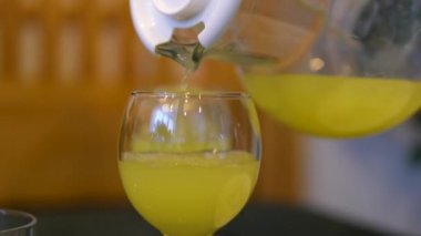 Yarım mandalinadan bardağa el basıncıyla meyve suyu sıkmak, masadaki diğer tüm mandalinaların arkaplanını görmek. Yüksek kalite 4k görüntü