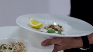 Erkek garson ziyafette servis yapıyor ve tabakta et atıştırmalığı tutuyor. Restoranda garsonluk yapıyor. Pirinç vermicelli Asya mutfağı