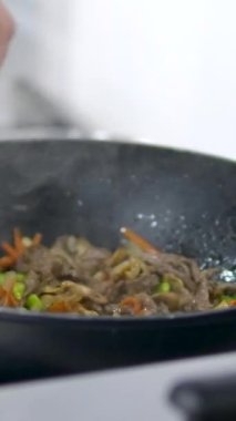 Hindi eti, erişte, paprika, mantar ve havuçlu waok yemek çubuklarıyla servis edilen siyah arka planda vermicelli udon. Yüksek kalite 4k görüntü