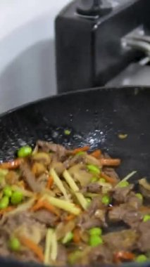 Hindi eti, erişte, paprika, mantar ve havuçlu waok yemek çubuklarıyla servis edilen siyah arka planda vermicelli udon. Yüksek kalite 4k görüntü