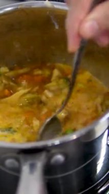 Elinde servis kaşığı ve tavası olan güzel bir kız. Genç kız çorba yapmayı öğreniyor. Siyah önlüklü ve şapkalı genç bir kadın mutfakta yemek hazırlıyor..