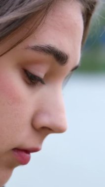 Bir nehrin arka planında genç bir kızın yüzü, aşağı inmiş, cep telefonuna bakıyor, haberleri okuyor, aletlere doğadan daha fazla zaman harcıyor, aletlere bağımlı. 4k 