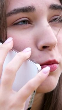Sokakta telefonda beyaz elbiseli neşeli bir kadın konuşuyor. Modern mutlu, sıradan gülümseyen, konuşan milenyum kızının portresi. Cep telefonuyla konuşan mutlu genç bayan.