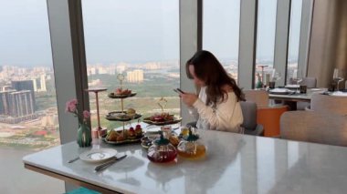 Ho Chi Minh şehrindeki lüks Vietnam tatilinde pahalı bir restoranda telefonu olan İngiliz kahvaltı kızı. Yüksek kalite 4k görüntü