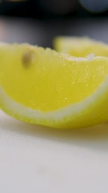Şam bıçağı sulu limon keser. Meyve suyu kesme tahtasına akıyor. Arka planda limonlar var. Sarı renk. Yavaşça yakınlaştır. Beyaz arka planda taze limon dilimi. Limonkırpma yolu