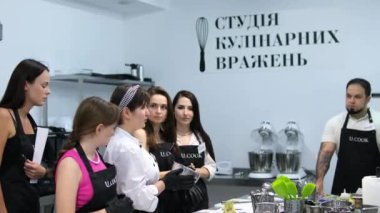 Yemek kursu. Mutfak sınıfı. Çok ırklı mutlu genç kadın öğrencilerden oluşan bir grup aşçılık okulunda aşçılık dersleri alıyor. Mutfak deneyimi stüdyosu. UCOOK Ukrayna Vinnitsa 08.04.2024
