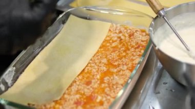 Mutfaktaki kadın lazanya hazırlıyor, peynir ekliyor kıyma ve pita ekmeği serpiştiriyor. Lazanya pişirme işlemi aşama aşama mutfakta hamur köftesi heykeli yapmak. Yemek pişiren kız.. 