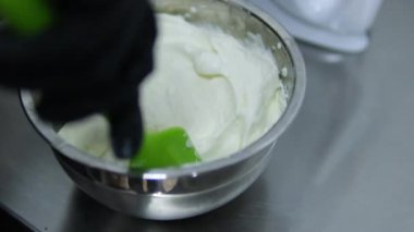 Kadın cam bir kasede tiramisu tatlısı hazırlıyor. Yanında da mutfak kasesi var. Adım adım tarif et. Tiramisu işlem yapıyor. 