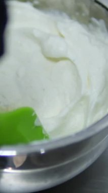 Kadın cam bir kasede tiramisu tatlısı hazırlıyor. Yanında da mutfak kasesi var. Adım adım tarif et. Tiramisu işlem yapıyor. 