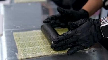 Kadın şef suşi yapar ve pirinç, kırmızı balık ve avokadodan rulo yapar. Yakından yemek pişirir. Suşi hazırlama süreci Master sınıfı. Adım adım Video seti