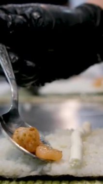 Kadın şef suşi yapar ve pirinç, kırmızı balık ve avokadodan rulo yapar. Yakından yemek pişirir. Suşi hazırlama süreci Master sınıfı. Adım adım Video seti