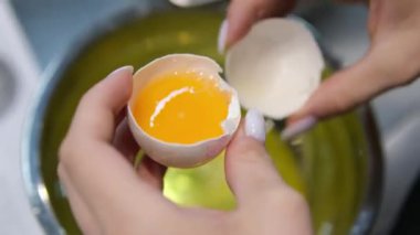 Yumurta beyazı, yumurta sarısı ve yumurta kabuklarını ayırmak için dişi eller yumurta kırıyor. Yüksek kalite 4k görüntü