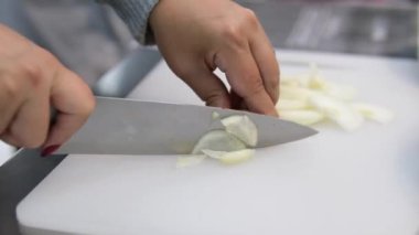 Yakın plan Şef, profesyonel mutfağın kesim yüzeyine iyi bir basınçla soğan doğruyor. Yüksek kalite 4k görüntü