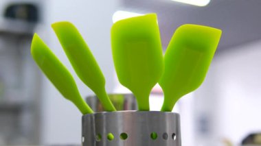 Yemek pişirmek için mutfak aletleri. Mans el bir mutfak kaşığı spatulası alır. Mutfak seti 4 silikon spatula ve ayakta duruyor.