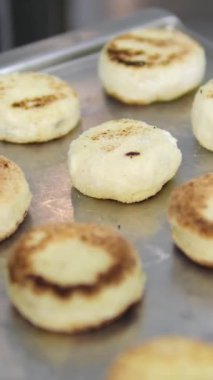 Peynirli krepler masada un içinde pişmesini beklerken, arka planda bir kadın kızartma tavasını ısıtıyor.