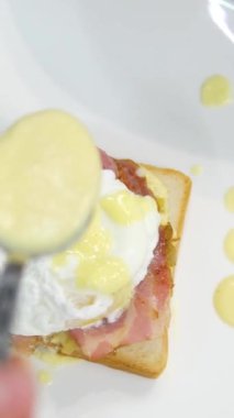 Benedict usulü yumurta haşlanmış yumurta soslu sandviç, yumurtalı Benedict ve Hollandaise sosu pişirme videosu. Yüksek kalite 4k görüntü