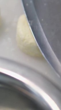 Peynirli krepler masada un içinde pişmesini beklerken, arka planda bir kadın kızartma tavasını ısıtıyor.