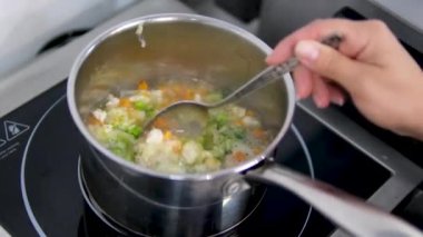 Bir tencerede sebze çorbası, havuç, patates, karnabahar ve kaşıkla brokoli pişir. Yüksek kalite 4k görüntü