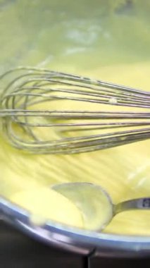 Çırpılmış sarı peynir soslu karıştırma, yakın çekim. Benedict yumurtaları için hollandaise sosu.