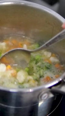 Bir tencerede sebze çorbası, havuç, patates, karnabahar ve kaşıkla brokoli pişir. Yüksek kalite 4k görüntü