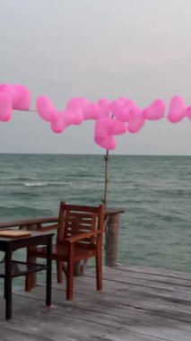Tahta bir köprünün kıyısında pembe balonlar. İskeleyi balonlarla boyayın. Tatili su balonlarıyla süsleyin.