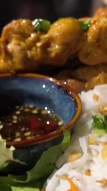 Bir sokak kafesinde akşam yemeği masanın üzerinde iki porsiyon şiş lik pirinç vermicelli sebzeli ve soslu plaj yemeği lüks restoran oteli dinlenmesi. zengin yaşam dikey videosu
