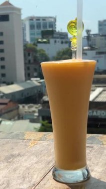 Ahşap masa sarı kokteylde. Sarı mango shake içmeye devam eder. Sıcak bir günde serinletici içecek. Cam Pipet ile tatlı mango suyu. Sabah kahvaltı sokak Cafe. Restoran İç tablo
