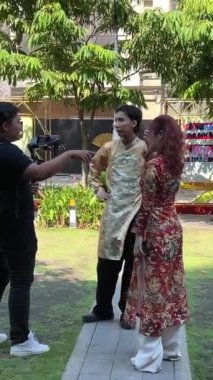 İyi kameralı Asyalı erkek fotoğrafçılar video çekimleriyle ilgili ana kursu çekiyorlar. Bir kız fotoğraf modeli üzerinde ulusal Vietnamlı kıyafetleri Ho Chi Minh Şehri Vietnam 08.22.2024