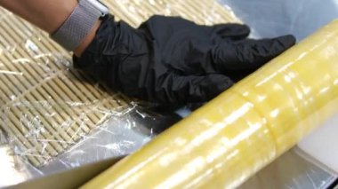 Yapışkan filme sarılı suşi hasırı. Evde suşi yapmak için hazır. Yüksek kalite 4k görüntü