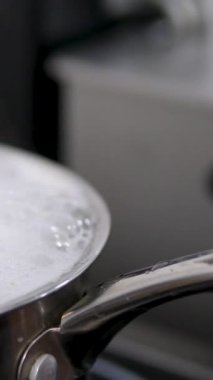 Kırsal ocakta haşlanan tencere ve sıvı su dışarı akıyor yanık ve kapağı çıkarıyor. Statik yakın çekim. Su kaynıyor ve köpük akıyor.