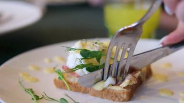 Sağlıklı sabah yemeği. Otelde kahvaltıda nefis haşlanmış yumurta yiyen bir adam. Erkek eli Benedict yumurtasının içinde yumurta sarısı, hollandaise sosu ve İngiliz çöreğinde ıspanak var.. 