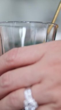 Karamelli süt karıştıran hassas kadın elleri masanın üzerinde bir bardakta. Yakın çekim kahve konsepti. Kahveyi bardakta yoğunlaştırılmış sütle karıştır.
