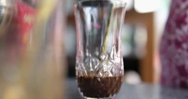 Karamelli süt karıştıran hassas kadın elleri masanın üzerinde bir bardakta. Yakın çekim kahve konsepti. Kahveyi bardakta yoğunlaştırılmış sütle karıştır.