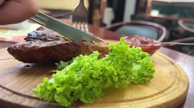 Ahşap tahta marul yaprağı ve ızgara biftek ince parçalara ayrılmış ve arka planda dilimler var. Yüksek kalite 4k görüntü