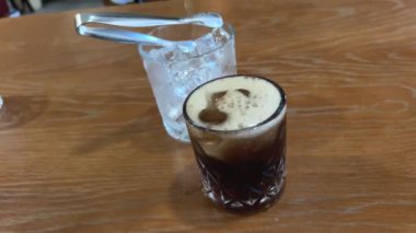 Yakın plan, bardağa içki dolduruyor. Kız cam bardağa döküyor. Kafede. Karbonatlı koyu içecek dökün.