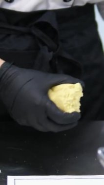 Maya hamurunu silikon hamurdan bir hamurun parçalarına ayırır ve onu elektronik ölçekte tartır. Ev yapımı pizza için hamur yoğurmak. Hamuru porsiyonlara böl