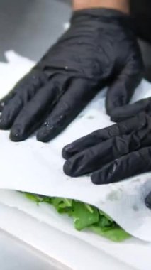 Elleri siyah eldivenli, akıllı saatli, salata hazırlayan, yeşillikleri kağıt havluyla silecek. Yüksek kalite 4k görüntü