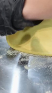 Fırıncı ellerinin yakın plan çekimi hamuru masanda merdaneyle yuvarlıyor. Yüksek kalite 4k görüntü