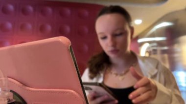 Kafede pembe laptoplu tablet ambalajıyla çalışan Avrupalı bir kız doğrudan saç yazısıyla çevrimiçi eğitim öğreniyor ve not defterine önemli cümleler yazıyor. Vietnam Ho Chi Minh Şehri 09.09.2024