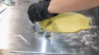 Fırıncı ellerinin yakın plan çekimi hamuru masanda merdaneyle yuvarlıyor. Yüksek kalite 4k görüntü