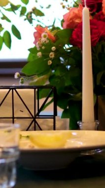 Masa bardakları, çiçekler, mum restoranda servis edilen tabaklar. Yüksek kalite 4k görüntü