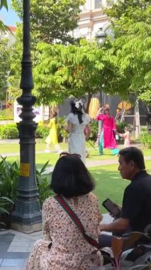 Central Caddesi 'ndeki geleneksel Vietnamlı aileler çimenlerin üzerinde yürüyorlar güzel parlak elbiseli kadınlar güneşte fotoğraf çekiyorlar erkekler bekliyor Ho Chi Minh Şehri Vietnam 09.30. 2024