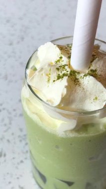 Frappuccino ile dondurma ve kremalı Matcha çayı yeşil arka planda cam bardakta. Yanında da bir kase Matcha dondurması..