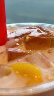 Plastik bardaktan buzlu latte içmek ve jöle parçaları ve buz küpleriyle karıştırılmış Asya içeceğiyle karıştırmak. Yüksek kalite 4k görüntü