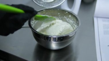 Tatlı pişirme krem peynir krem peynir peynir süt ürünü karışımına krem peynir ekle. Profesyonel kadın pastacı karıştırma kabına beyaz kremalı karışım ekliyor.