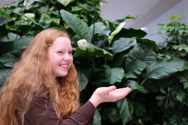 Genç kız el ilanında kırmızı saçlar açık beyaz ten pembe yanaklar elinizdeki görünmez nesneyi ilanınız için tutuyor. Yüksek kalite 4k görüntü