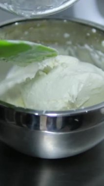 Tatlı pişirme krem peynir krem peynir peynir süt ürünü karışımına krem peynir ekle. Profesyonel kadın pastacı karıştırma kabına beyaz kremalı karışım ekliyor.