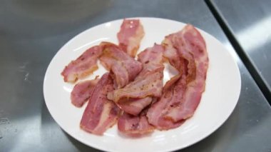 Dökme demir bir tavada yağla kızartılmış lezzetli domuz pastırması görüntülerini kapatın. Parlak, aromatik, kızgın tavada kıtır kıtır pastırma parçaları. Yüksek kalite 4k görüntü